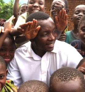 Malawi staff Mike smiling with kids around